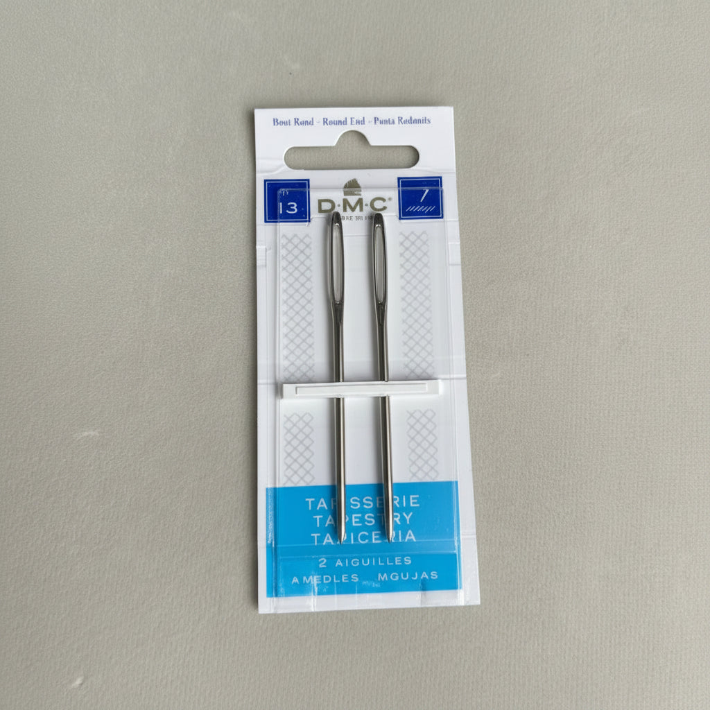 Two needles in a DMC branded packaging on a gray background