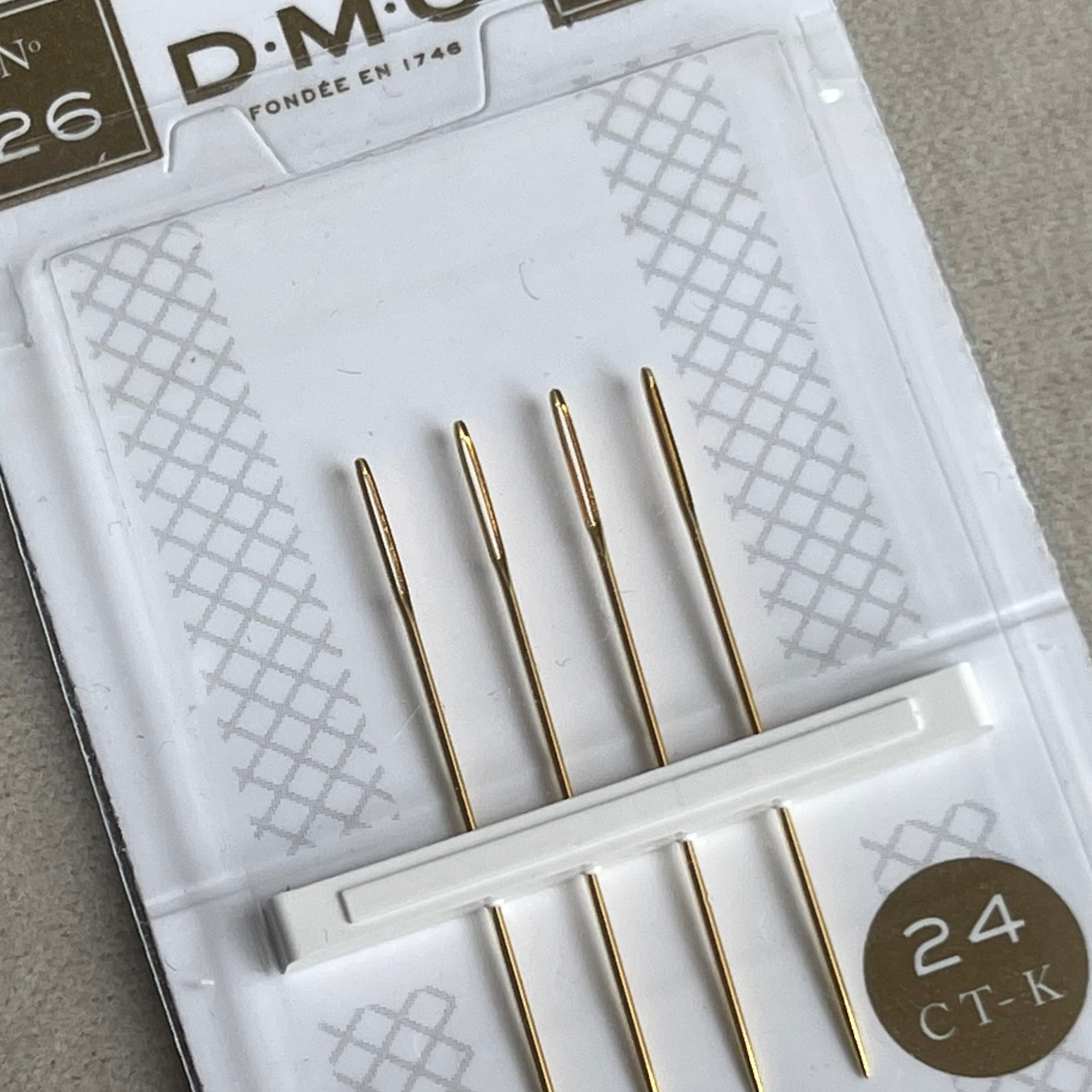 Packaged set of DMC needles on a gray background