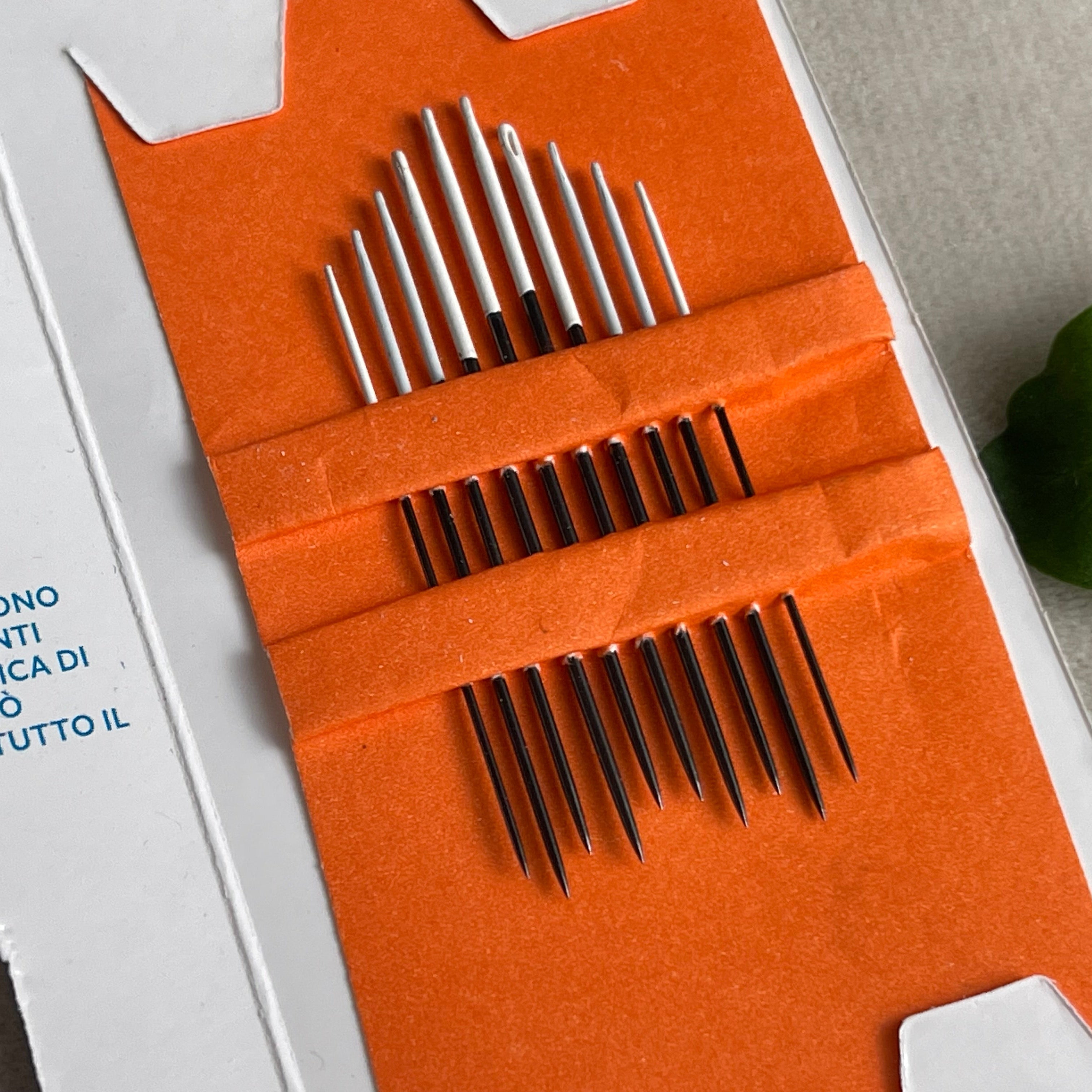 Set of metal needles in an orange case with a white background