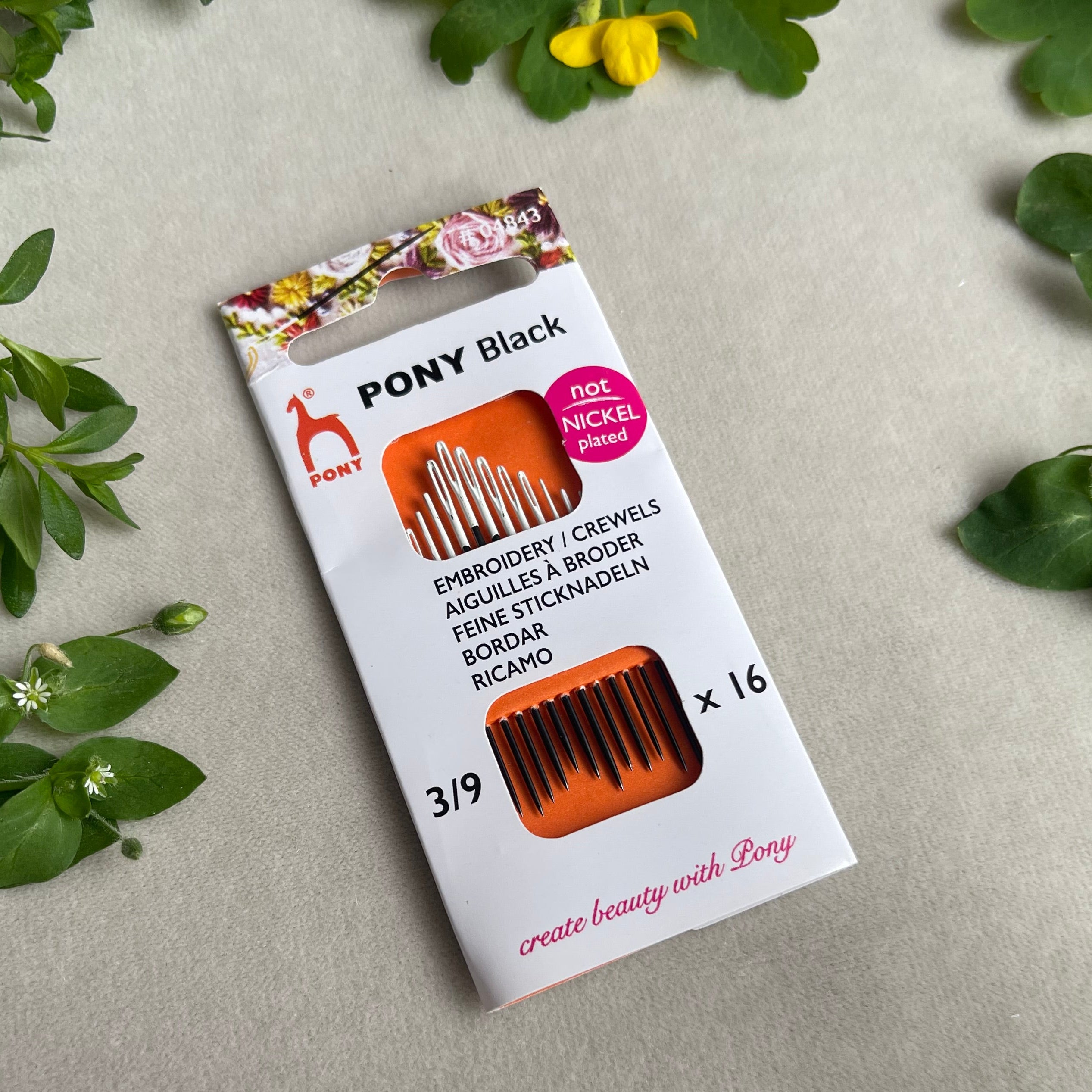 Pony Black embroidery threads packaging on a light gray background with green leaves.