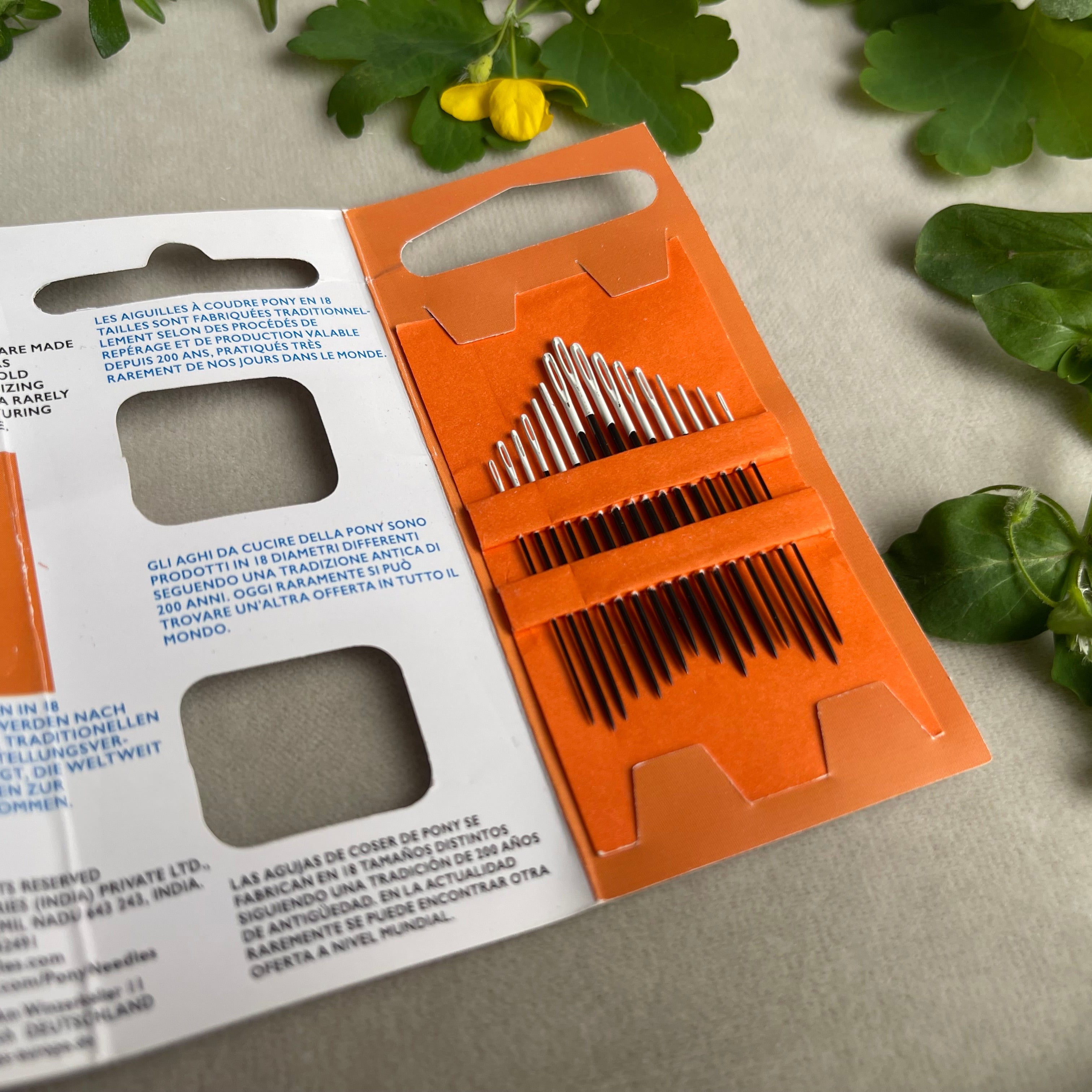Orange and white packaging of needles with green leaves in the background
