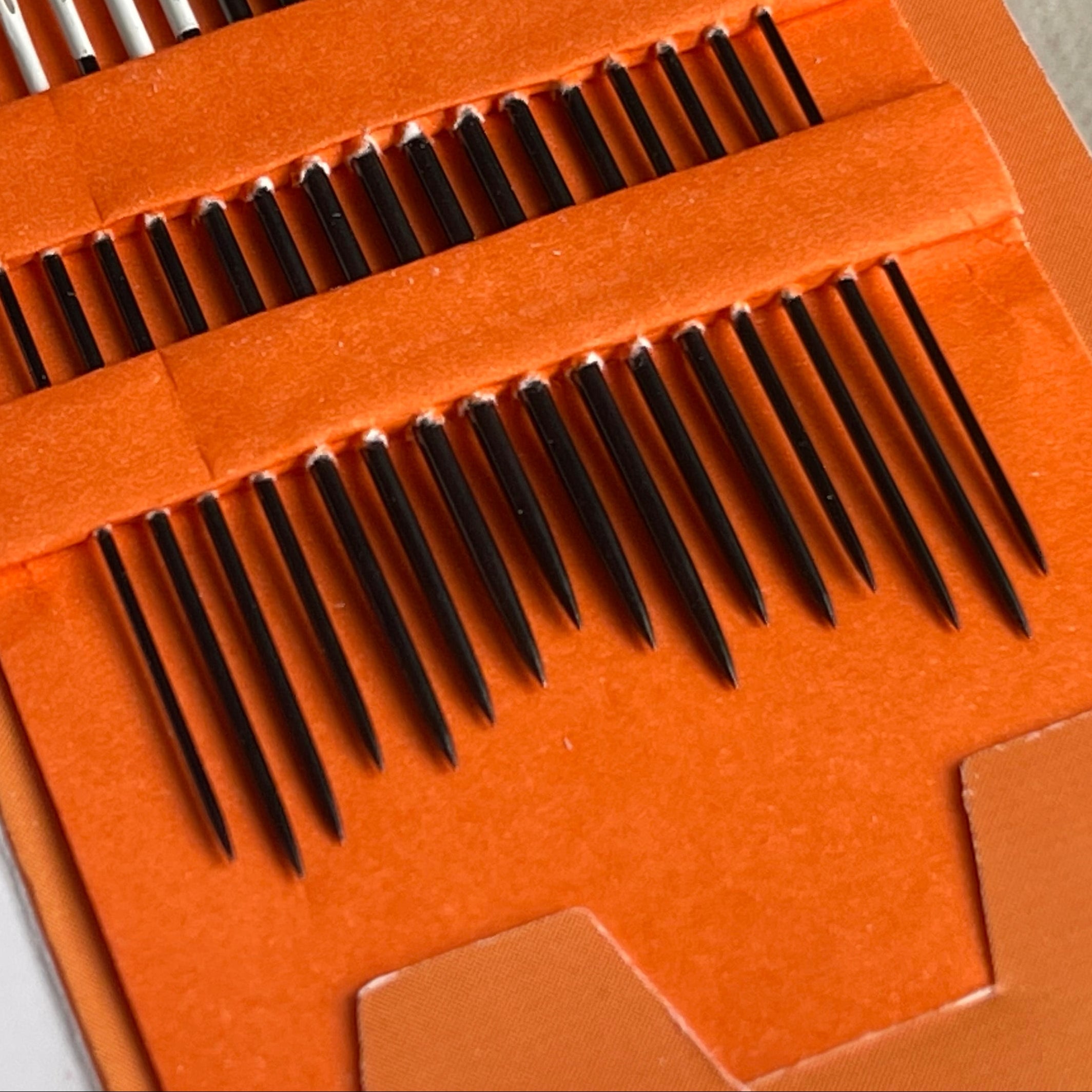 Set of metal needles in an orange case with a blurred background