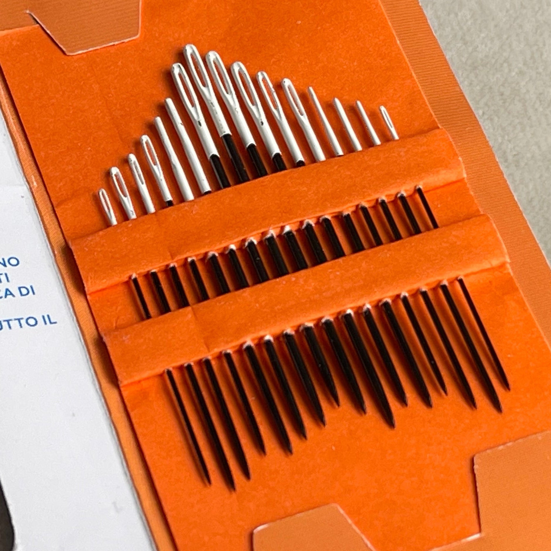 Orange packaging of hair clips with a white card and green leaves in the background