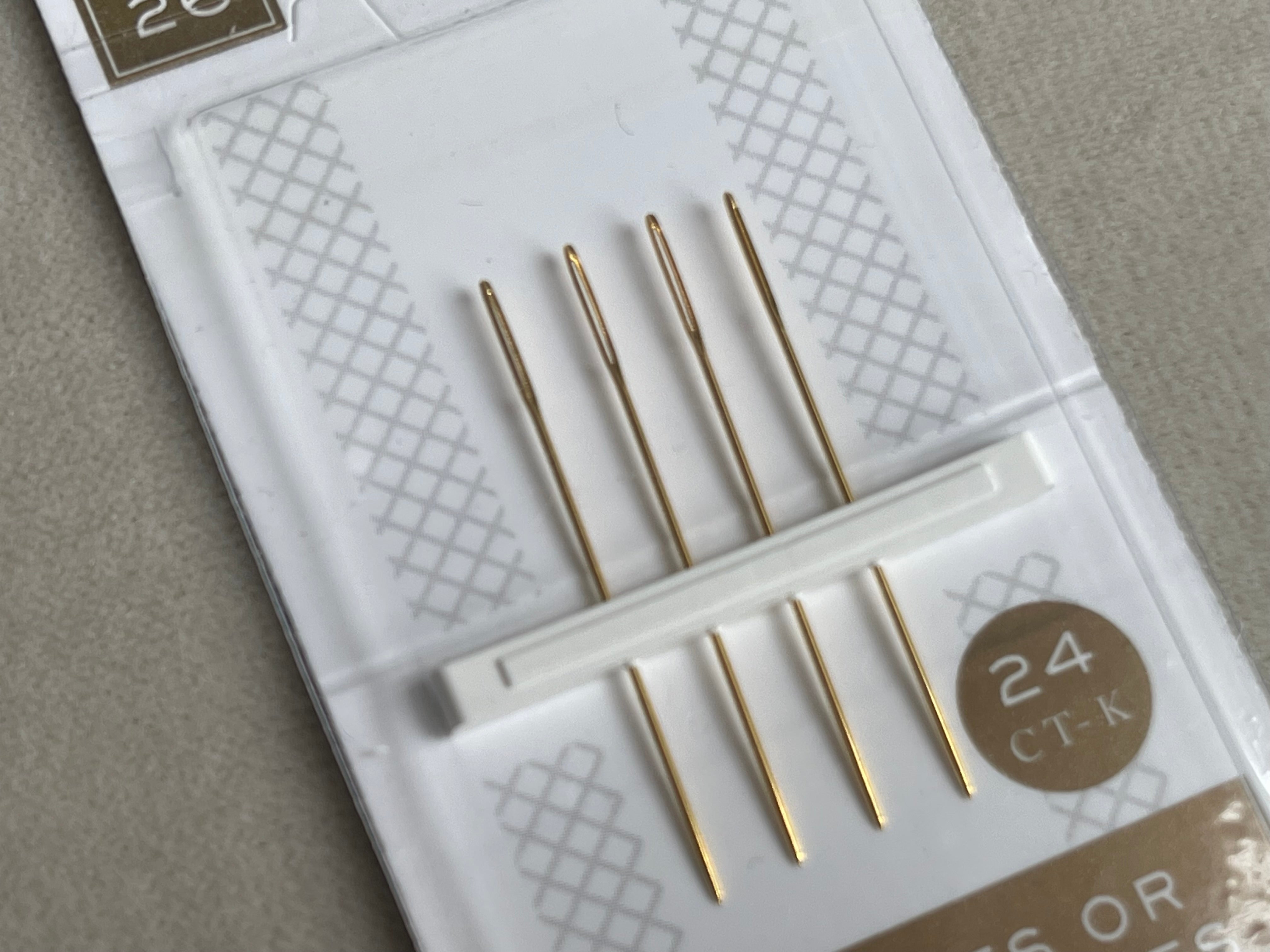 Set of gold crochet hooks in a clear plastic case on a gray background