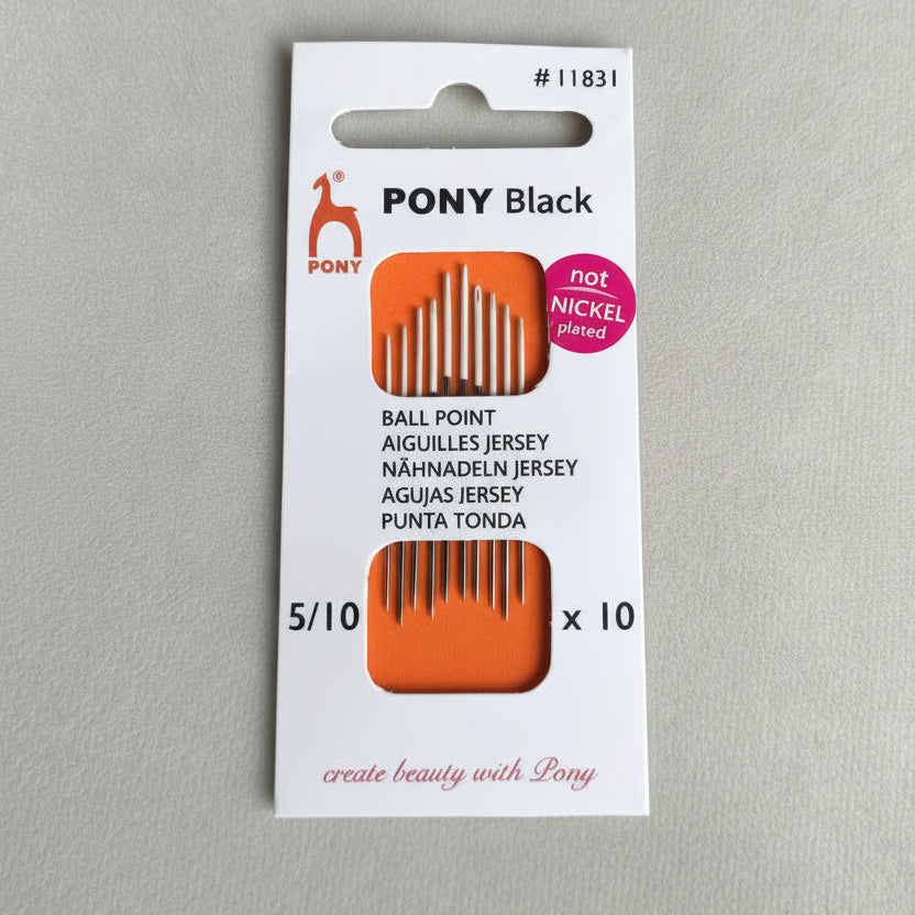 Pony hair black comb package on a gray surface with green leaves